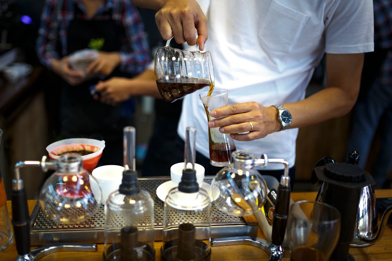 Services A barista carefully pouring brewed coffee into a clear glass in a coffee shop.