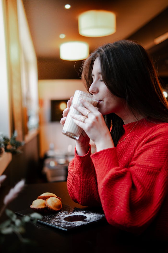 Crafting Captivating Headlines: Your awesome post title goes here A woman in a red sweater savors a warm latte at a cozy café in Valenciennes, France.