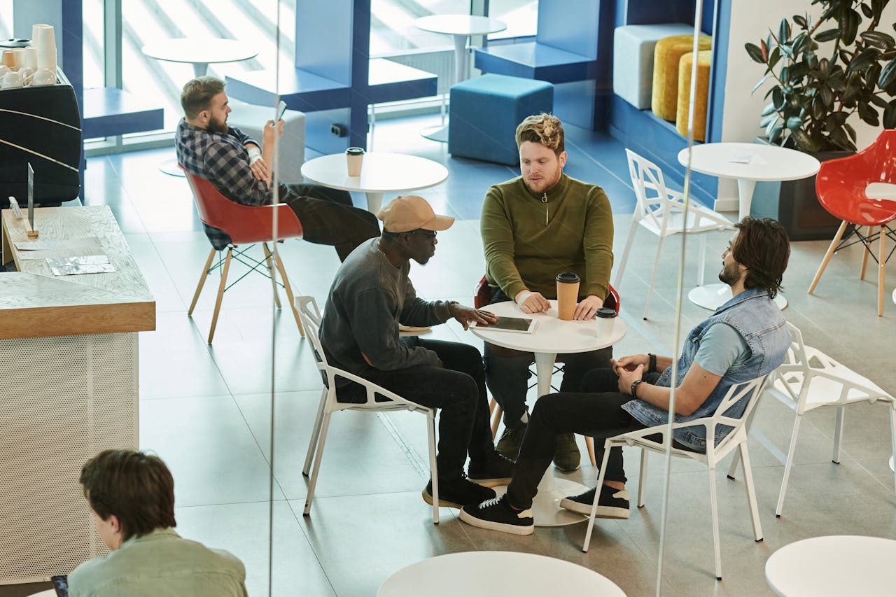 Mastering the First Impression: Your intriguing post title goes here A group of diverse friends enjoying a coffee break and conversation in a modern cafeteria setting.