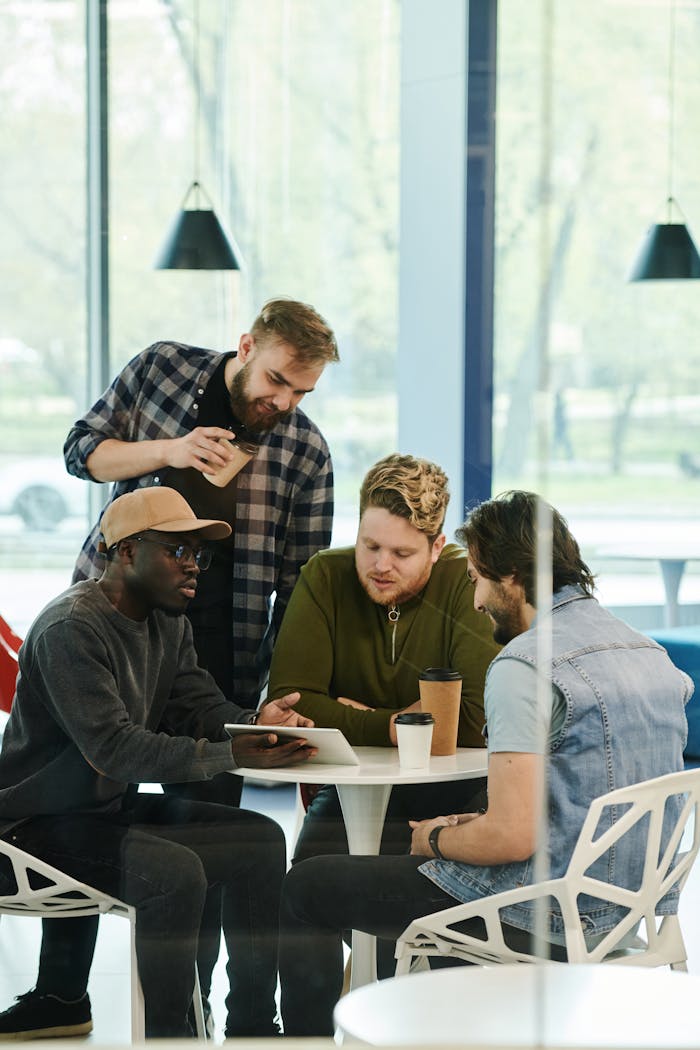 Services A multicultural group of young professionals collaborating over coffee in a modern setting.